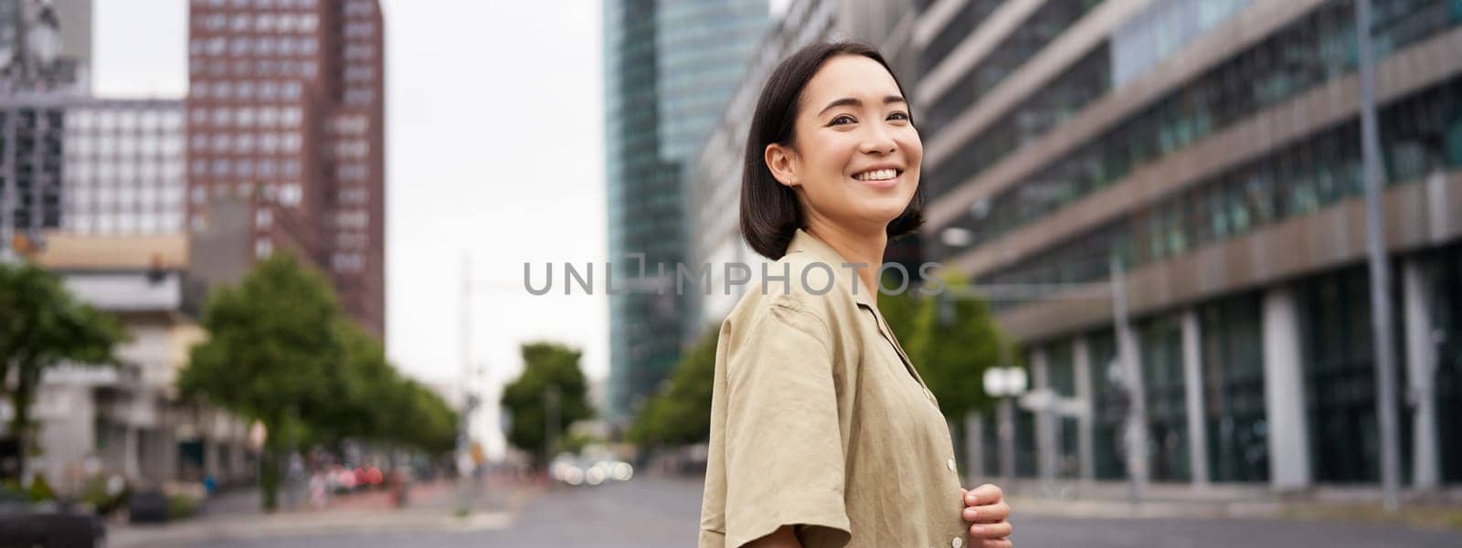 Outdoor shot of asian girl with laptop, going somewhere in city centre, walking on street, going to work by Benzoix