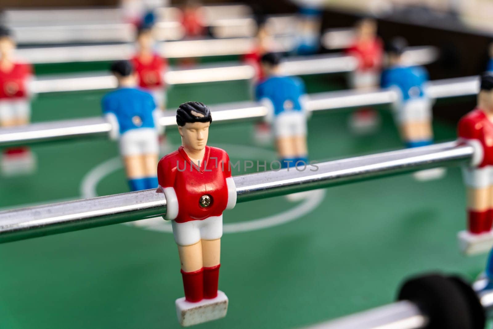 Table football. Close-up of figures of plastic players in a football match. red and blue players kick the ball.