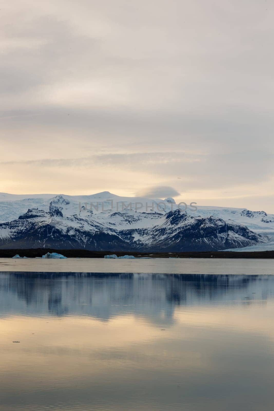 Ice covered hillsides and large scandinavian lake in arctic region of Iceland. Winter wonderland stunning route with incredible sundown light during golden hour, polar adventure.