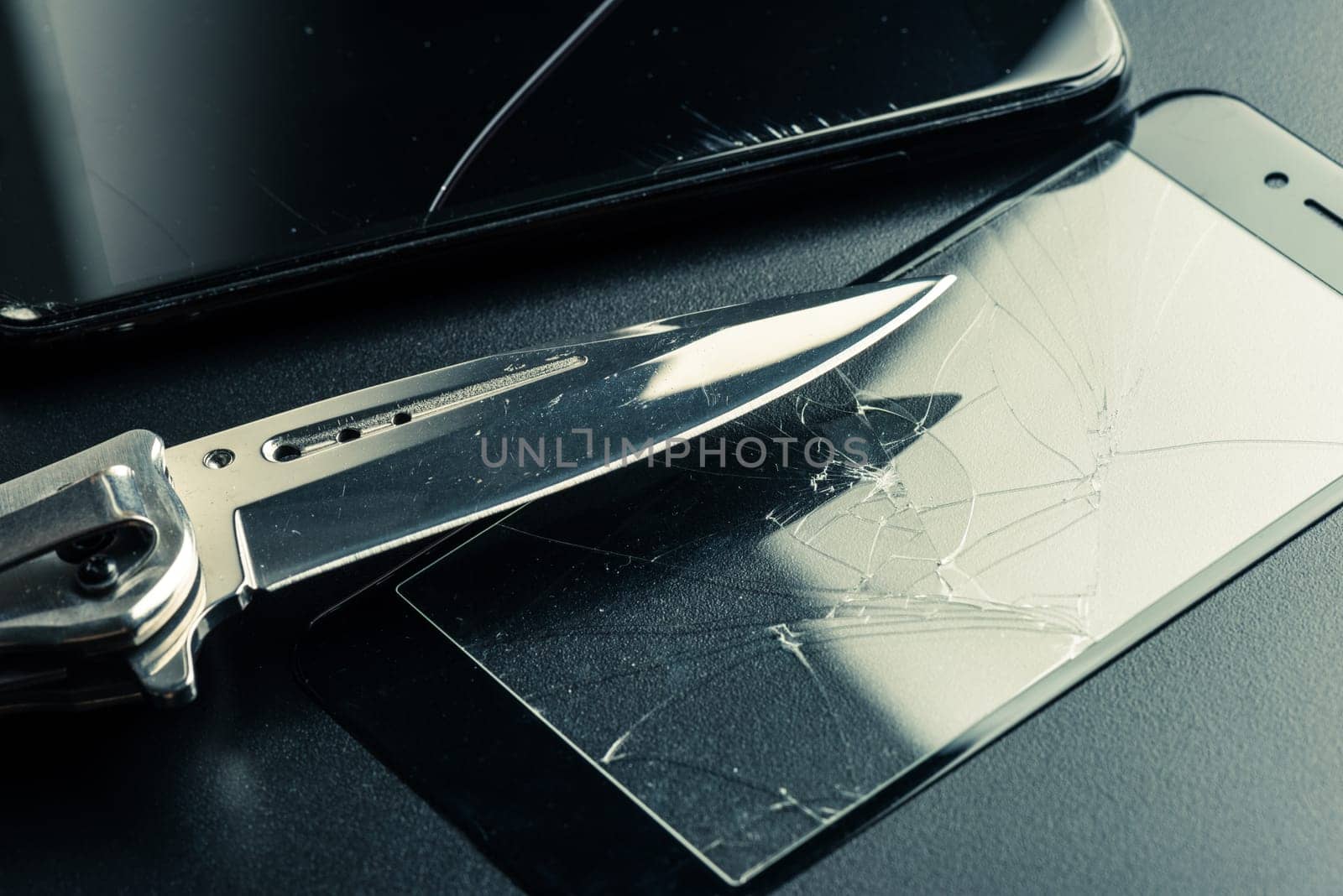 closeup broken tempered glass screen protector for smartphone. Testing the hardeness with knife.