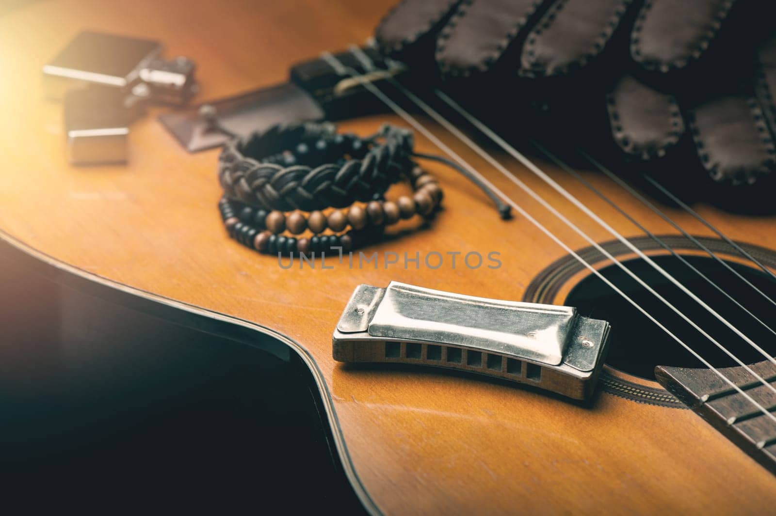 vintage wooden harmonica lying on an old acoustic guitar.