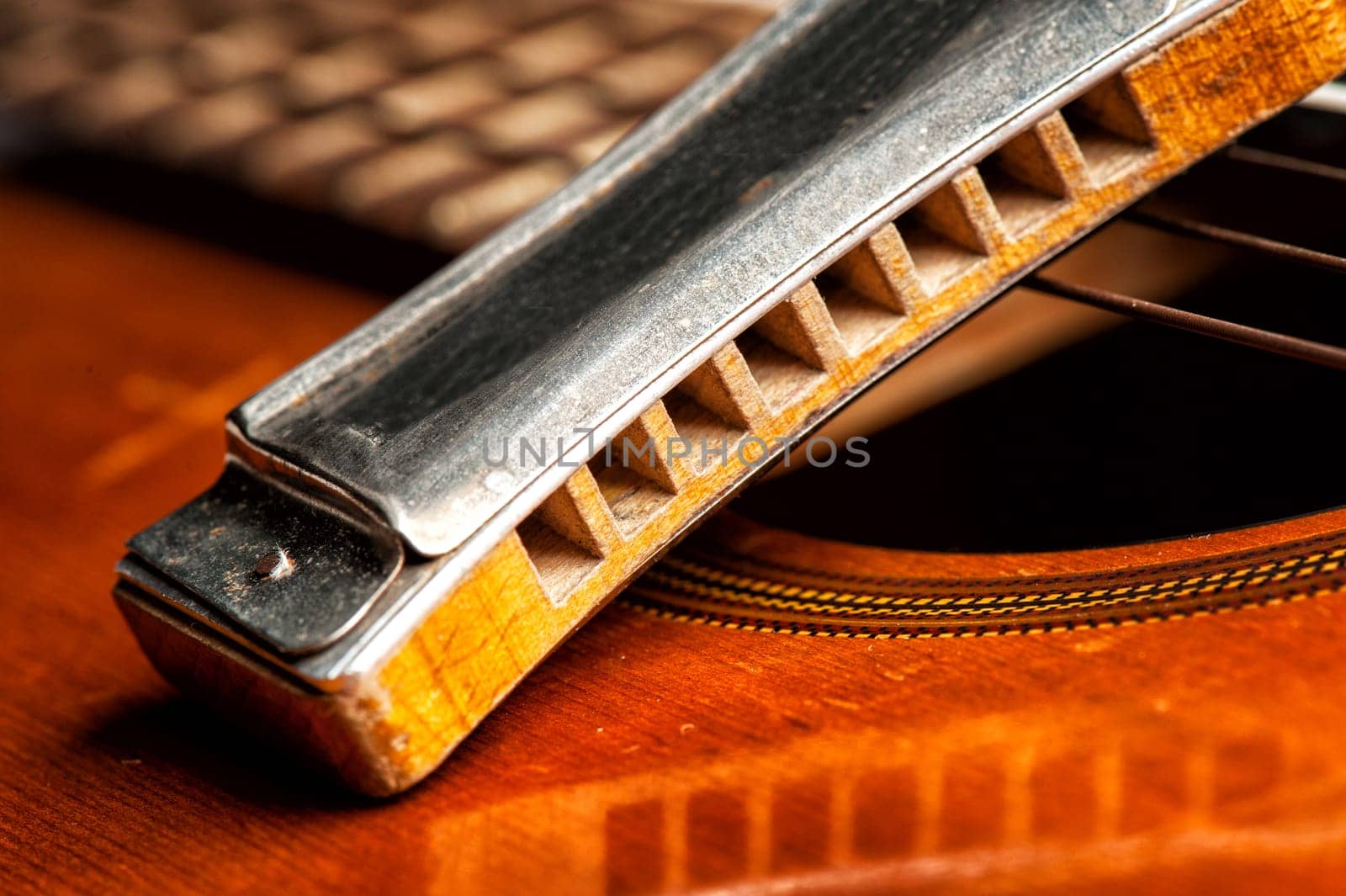 vintage wooden harmonica lying on an old acoustic guitar.