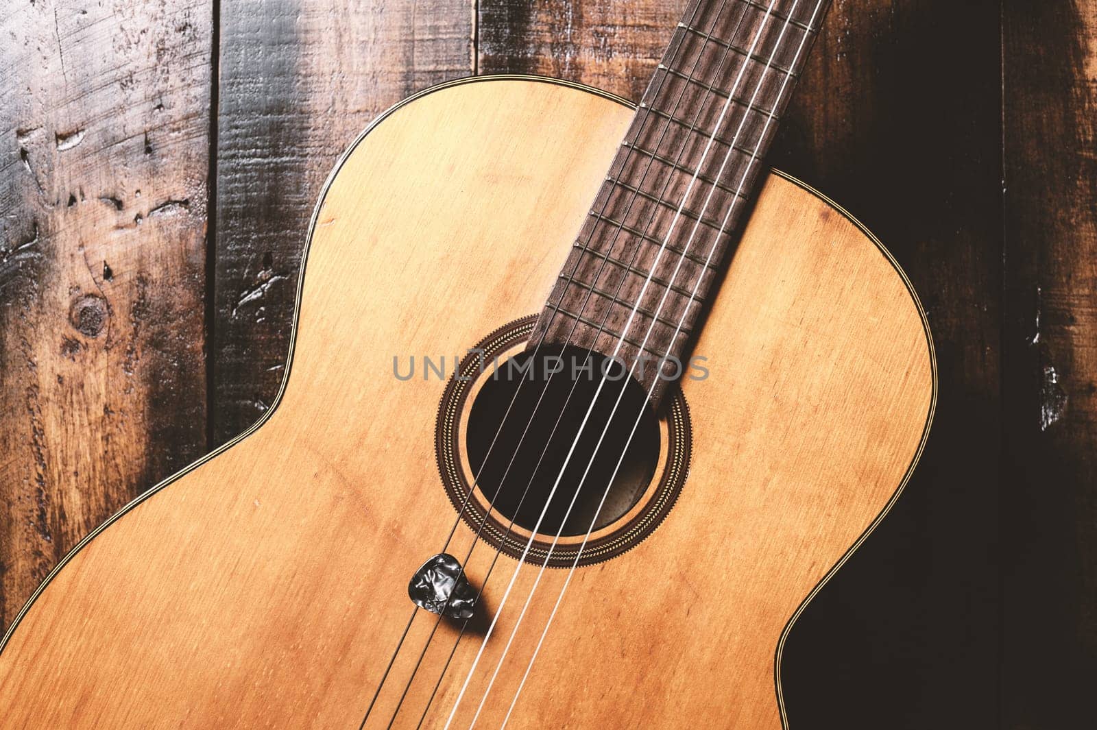 classical guitar with guitar pick on wooden background