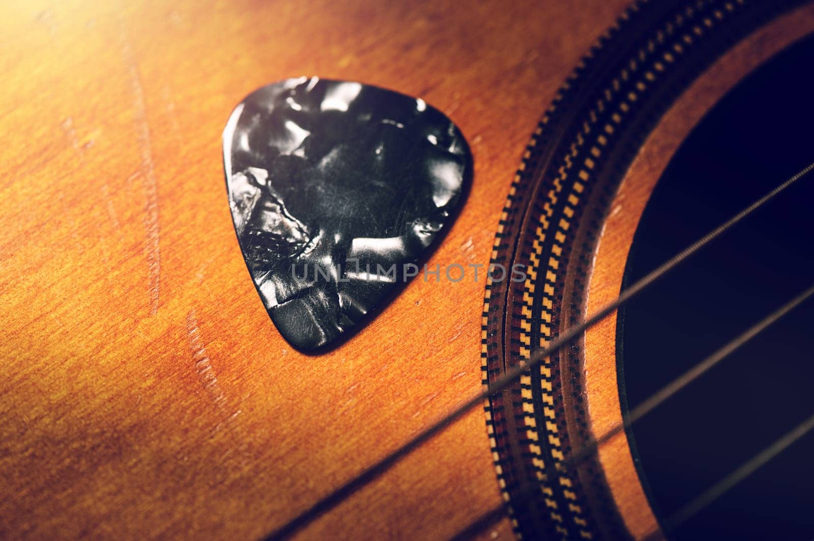Closeup guitar pick on an old classical guitar. A guitar pick is a plectrum used for guitars.