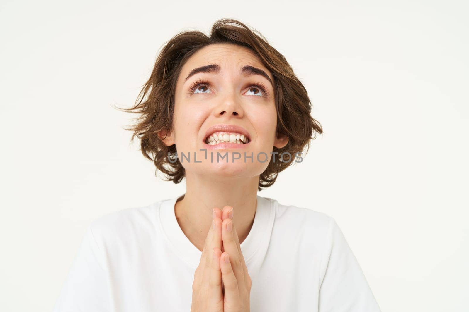Close up of woman praying, looking with begging face, asking for help, pleading, standing isolated over white background. Copy space
