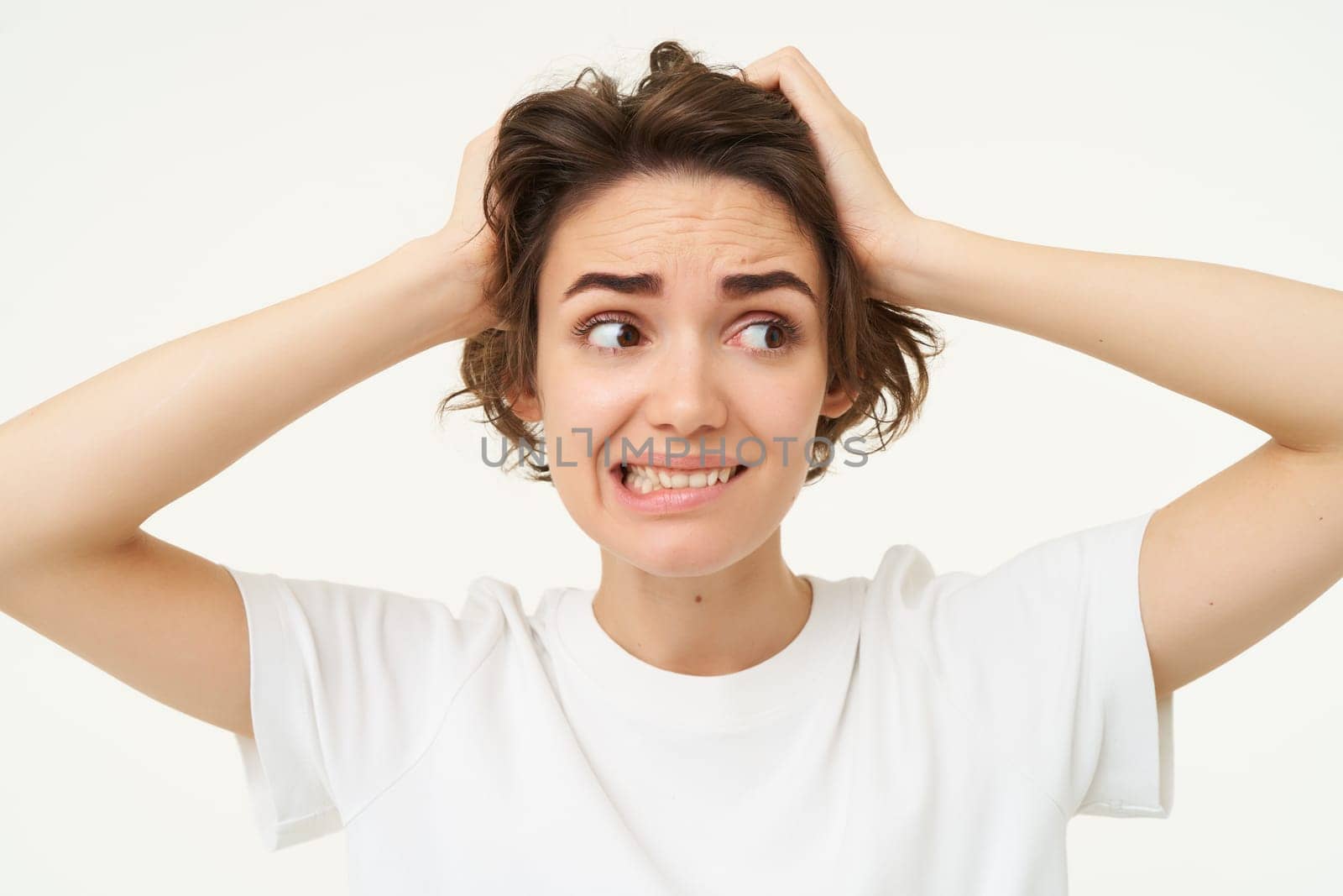 Close up of girl in panic, looking around, holding hands on head, facing trouble, complicated issue, standing over white background by Benzoix