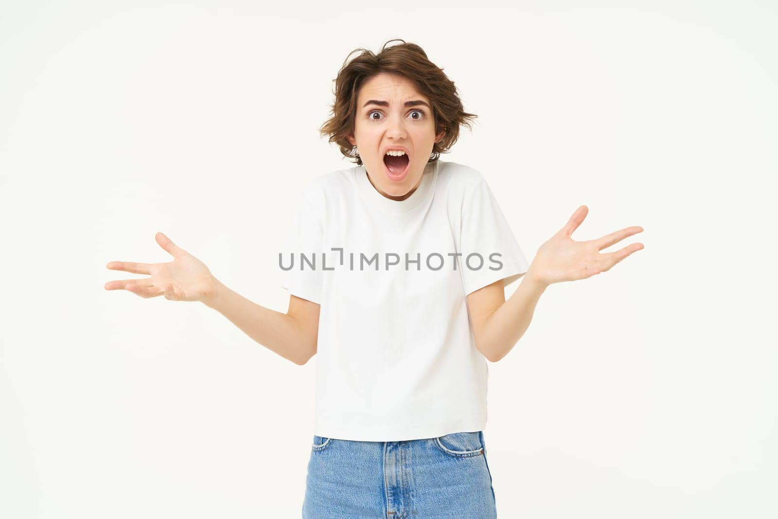 Frustrated young woman, looking upset and disappointed, complaining, screaming from distress and anger, standing over white studio background by Benzoix