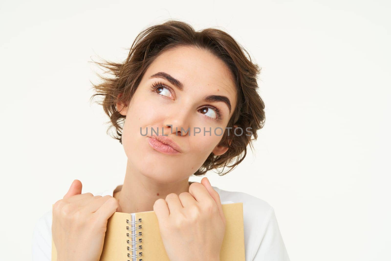 Portrait of happy, beautiful woman holding planner, making notes, doing her homework, standing over white background.