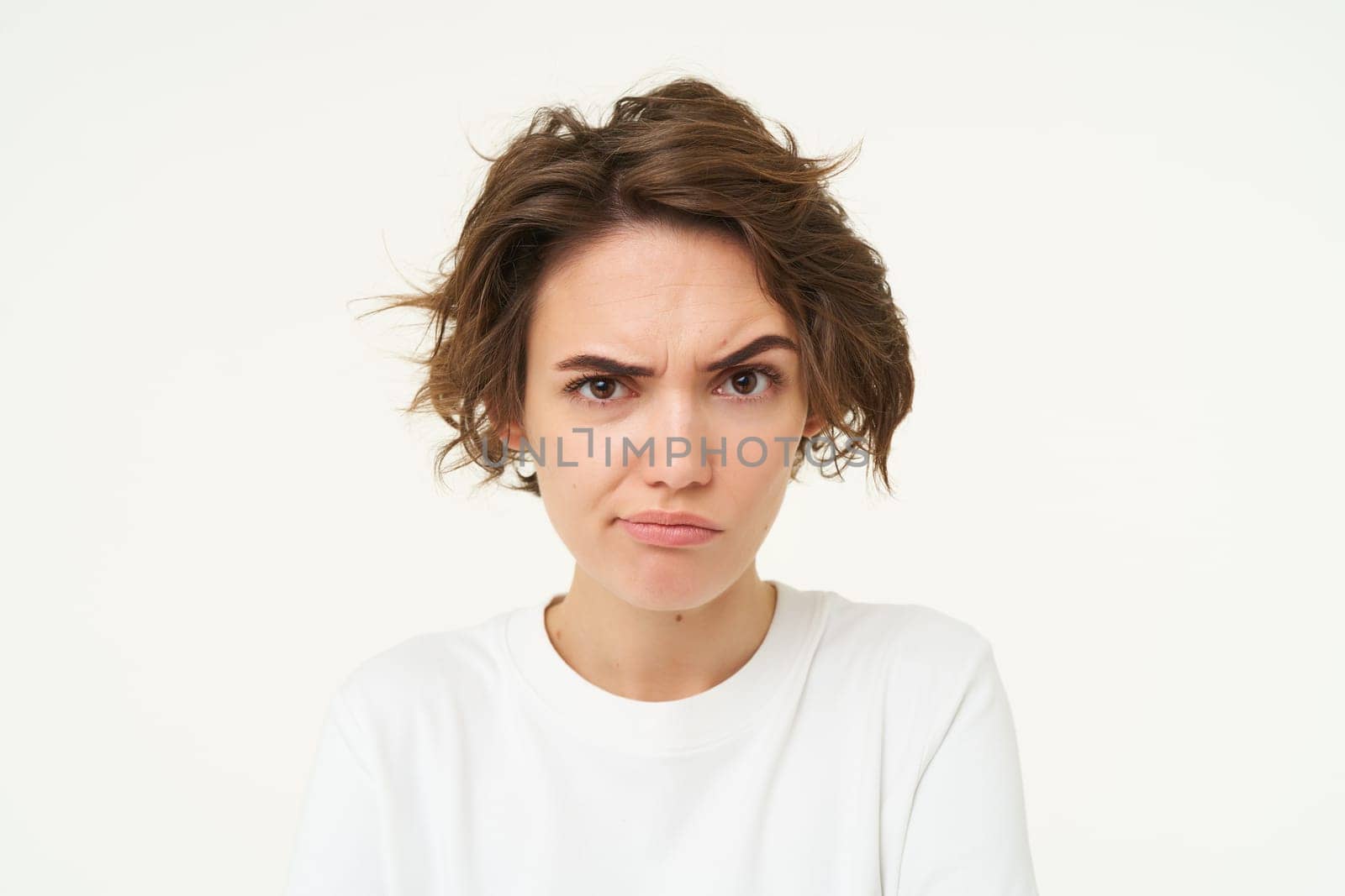 Portrait of serious, thoughtful woman with frowning face, looking suspicious, posing over white studio background.