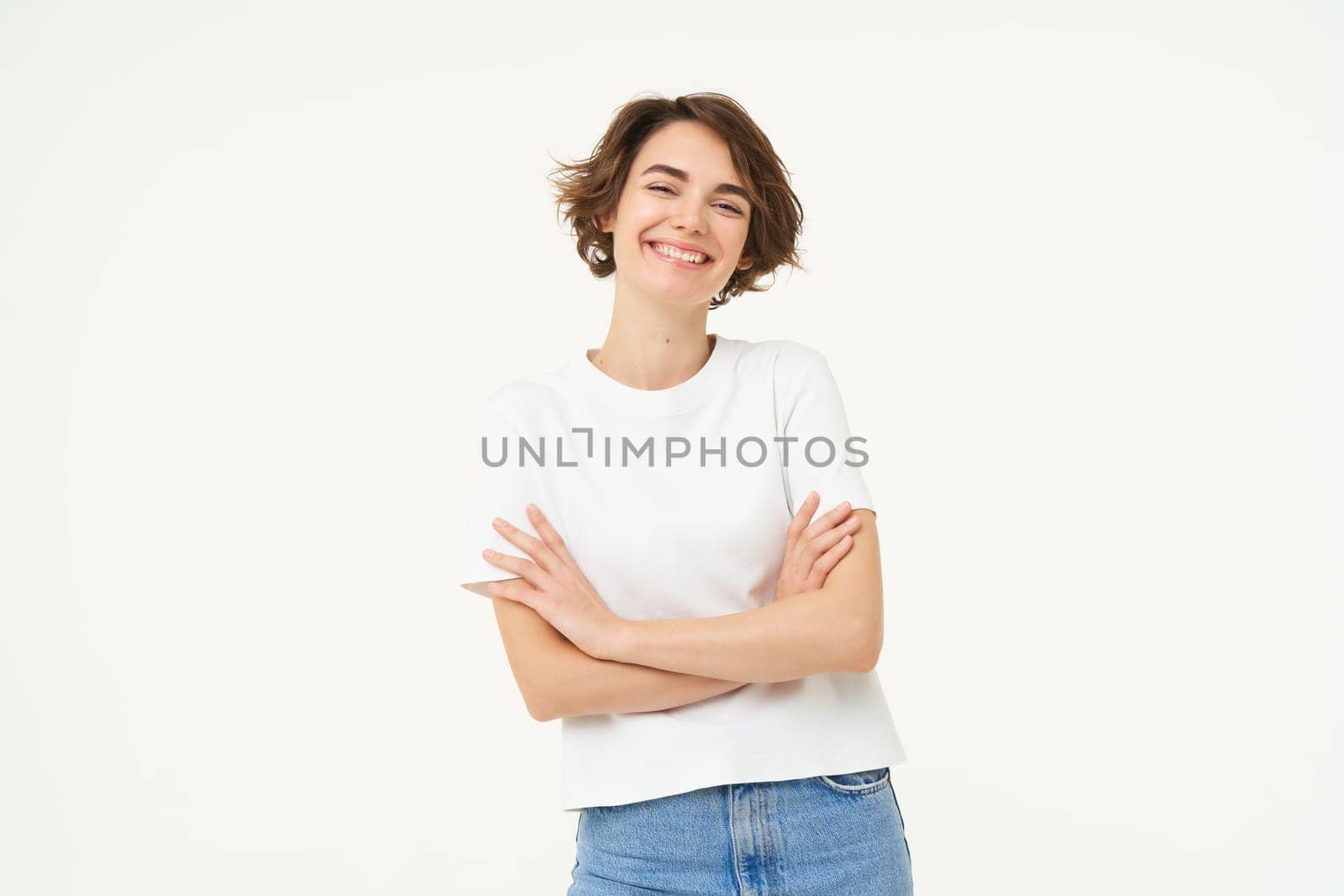 Portrait of cheerful woman laughing and smiling, cross arms on chest, standing in confident power pose, young professional concept, white studio background.