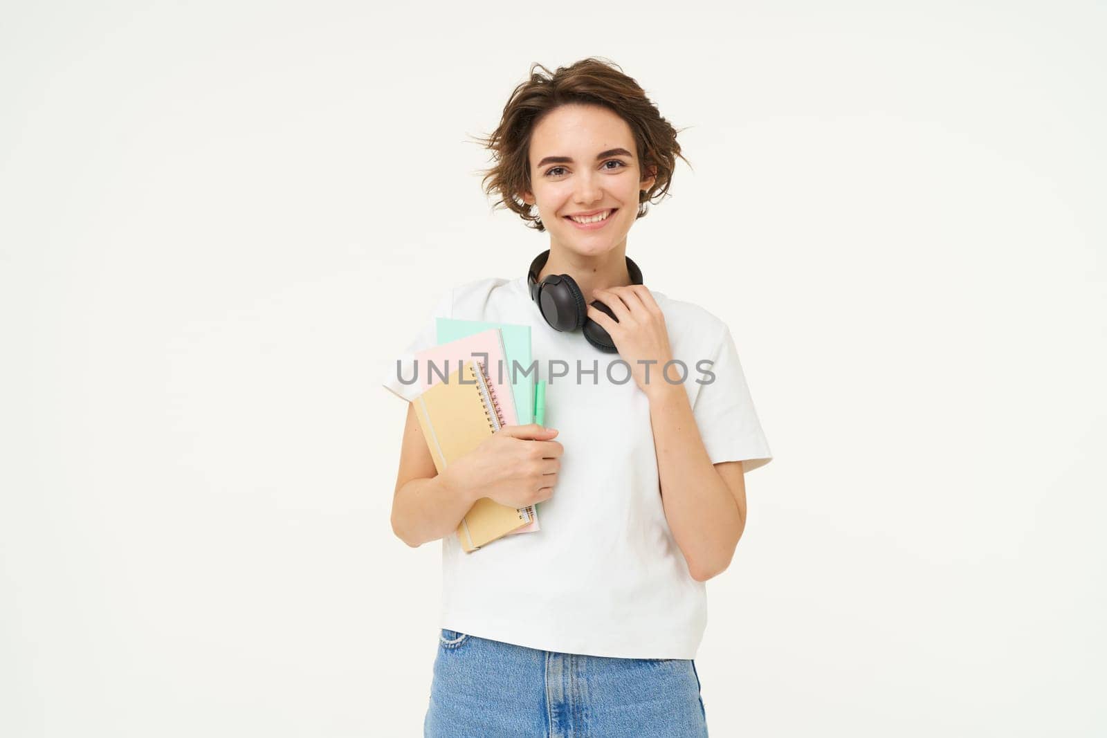 Image of stylish, modern girl student, holding workbook, documents. Woman teacher with papers standing over white background.