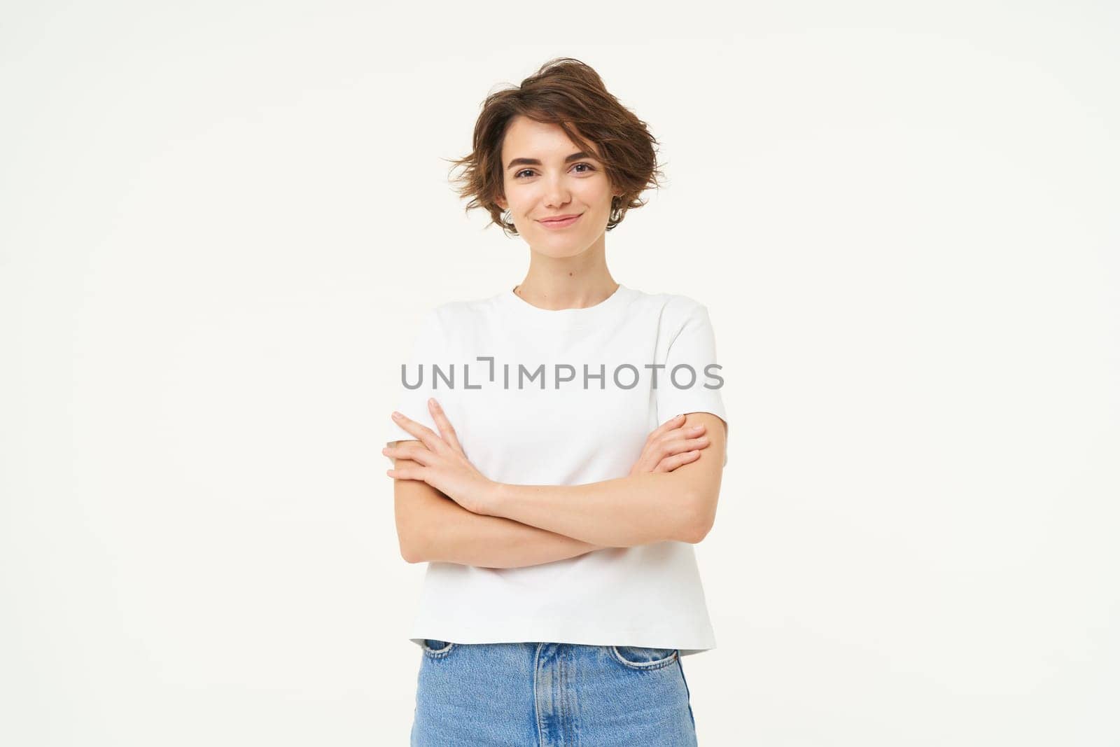 Portrait of woman standing in power pose, confident expression, cross arms on chest and smiles, stands over white background.