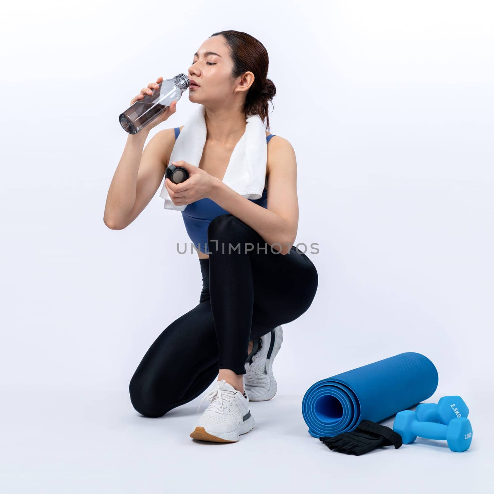 Athletic and sporty asian woman resting and drink water after intensive cardio workout training. Healthy exercising and fit body care lifestyle pursuit in studio shot isolated background. Vigorous