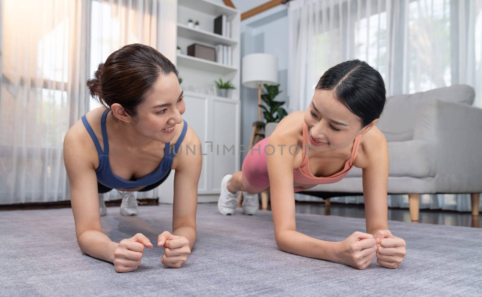 Fit young asian woman planing on the living room floor with her trainer or exercise buddy. Healthy lifestyle workout training routine at home. Balance and endurance exercising concept. Vigorous