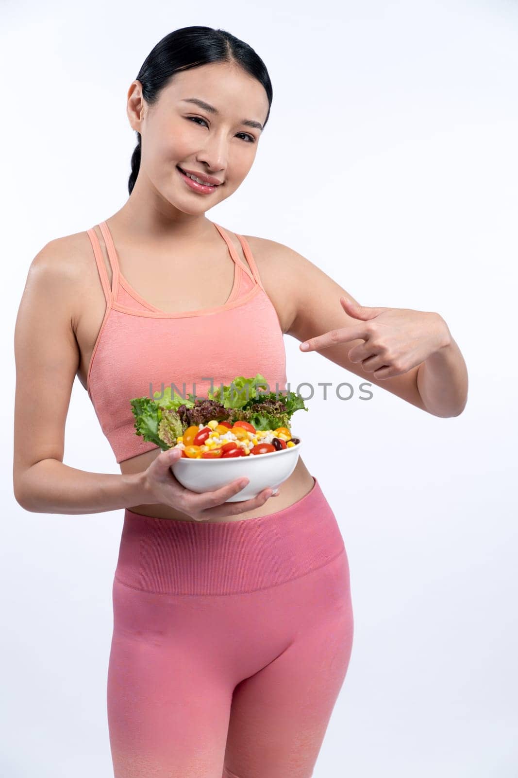 Asian woman in sportswear holding salad bowl on isolated background. Vigorous by biancoblue