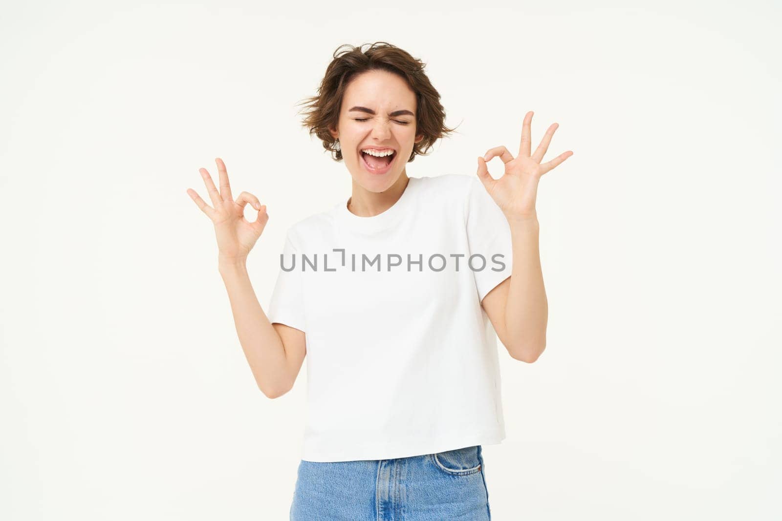 Image of smiling, happy girl shows okay, ok sign, recommending, like and approve something good, standing over white background by Benzoix