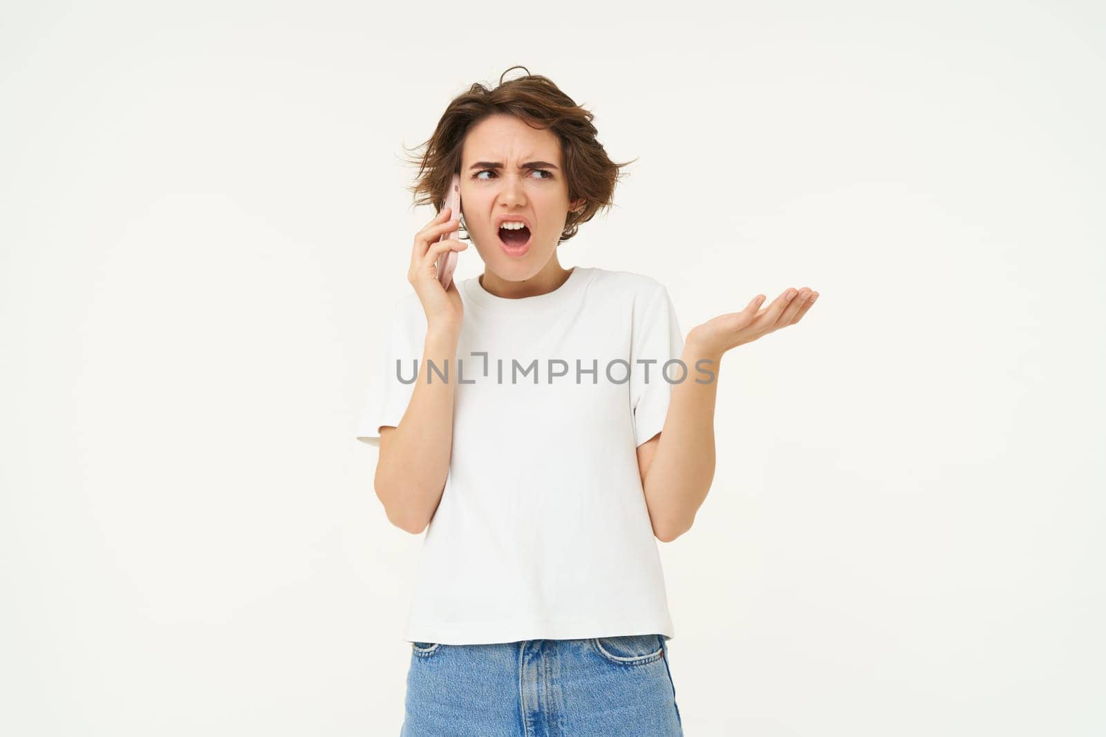 Portrait of angry lady talking on phone, frustrated woman shouting at her mobile telephone, standing over white background by Benzoix