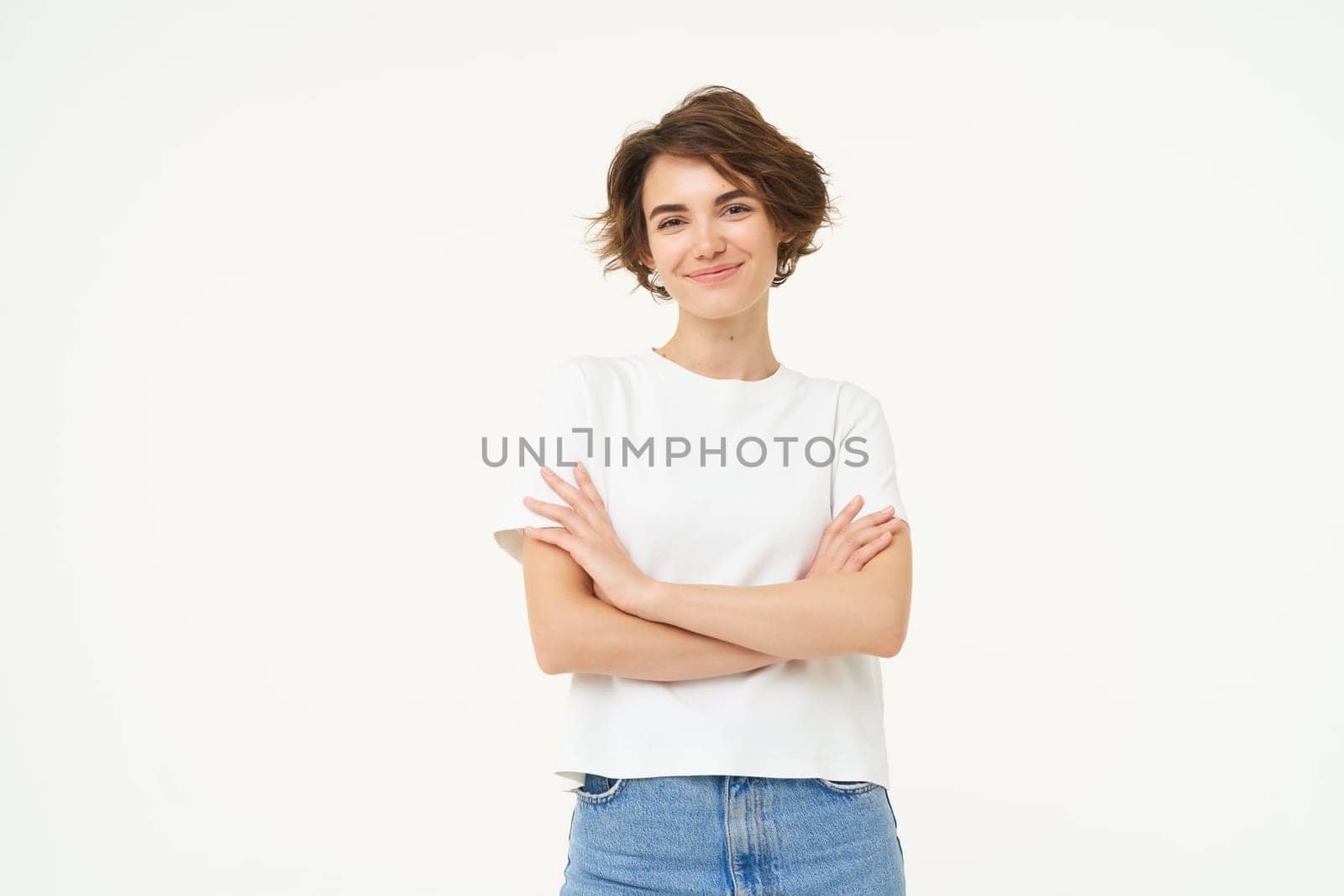 Portrait of woman standing in power pose, confident expression, cross arms on chest and smiles, stands over white background.