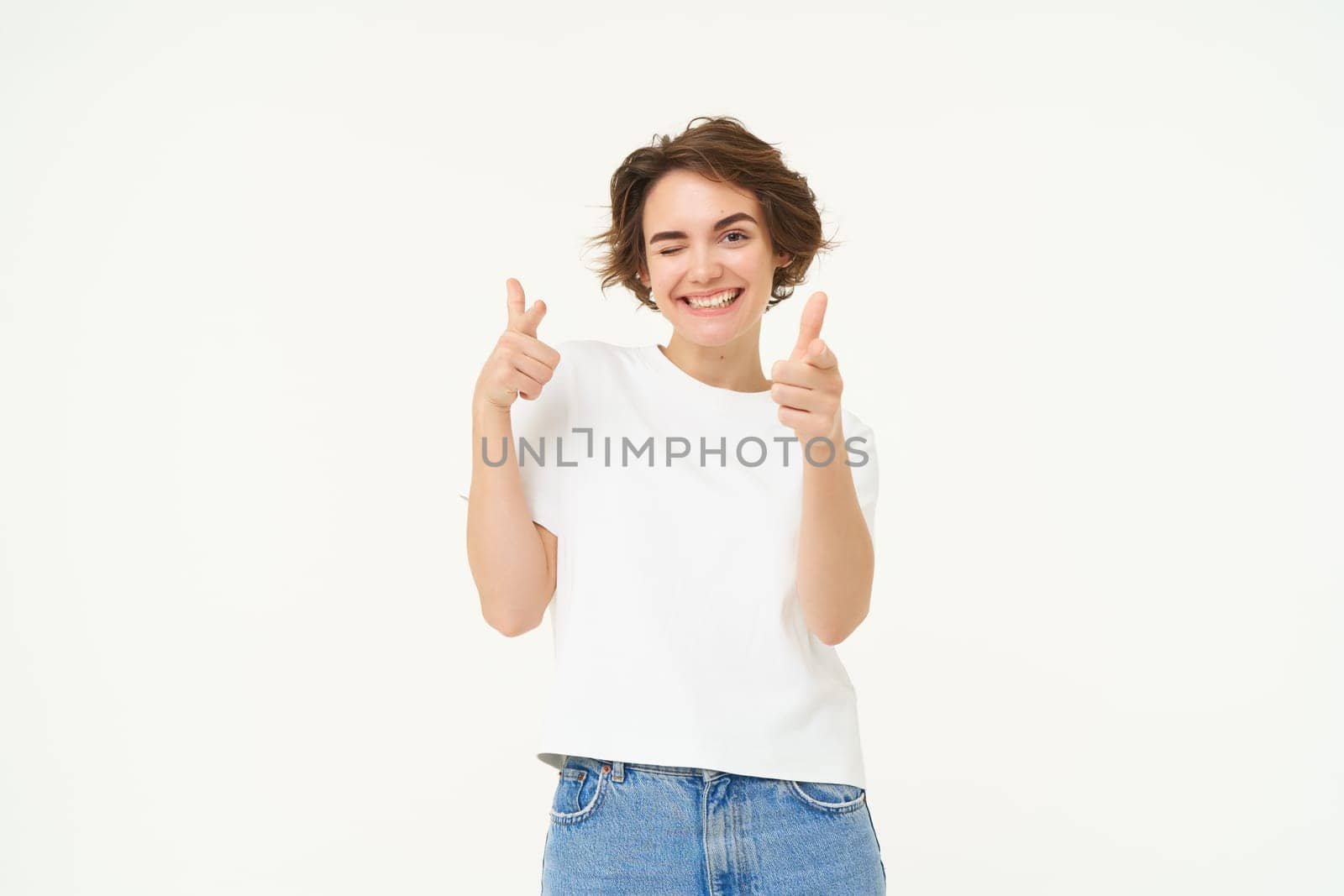 Portrait of cheerful young woman, shows thumbs up in approval, like something good, nod in approval, looking confident, standing over white background.