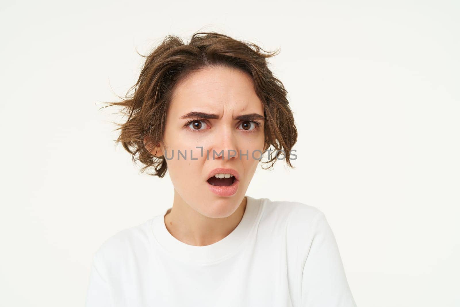 Close up portrait of shocked woman looking insulated, bothered by something, pouting and sulking, posing over white background. copy space