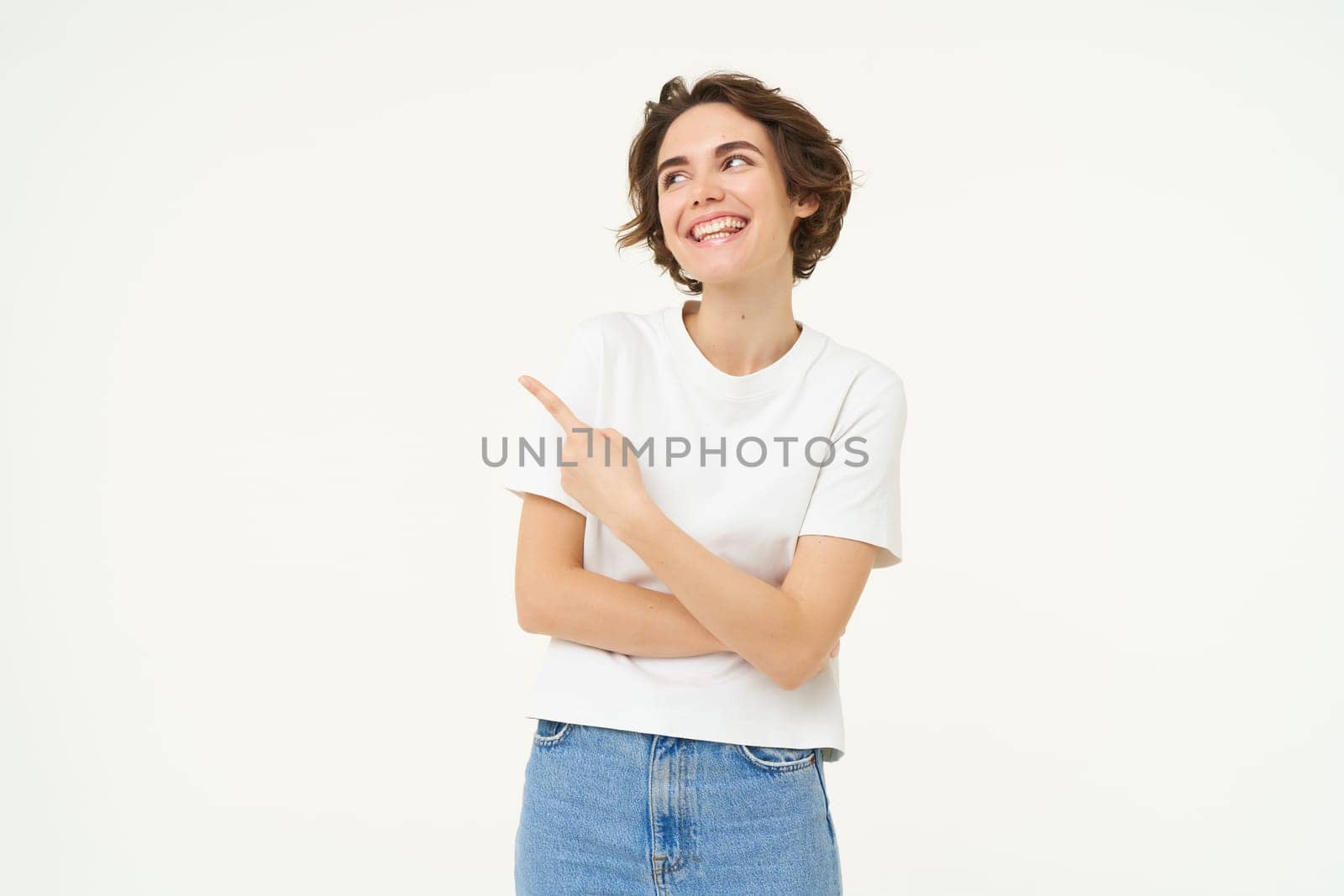 Portrait of brunette girl showing banner, pointing finger left, advertising, standing over white background.