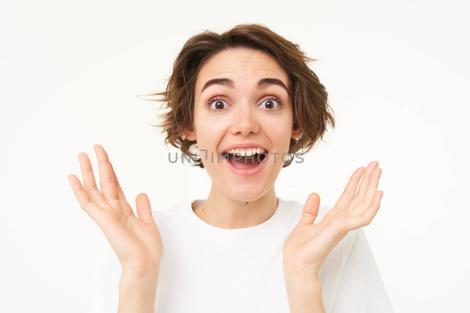 Close up portrait of excited woman, gasping and smiling, looking surprised, amazed by great news, isolated over white background.