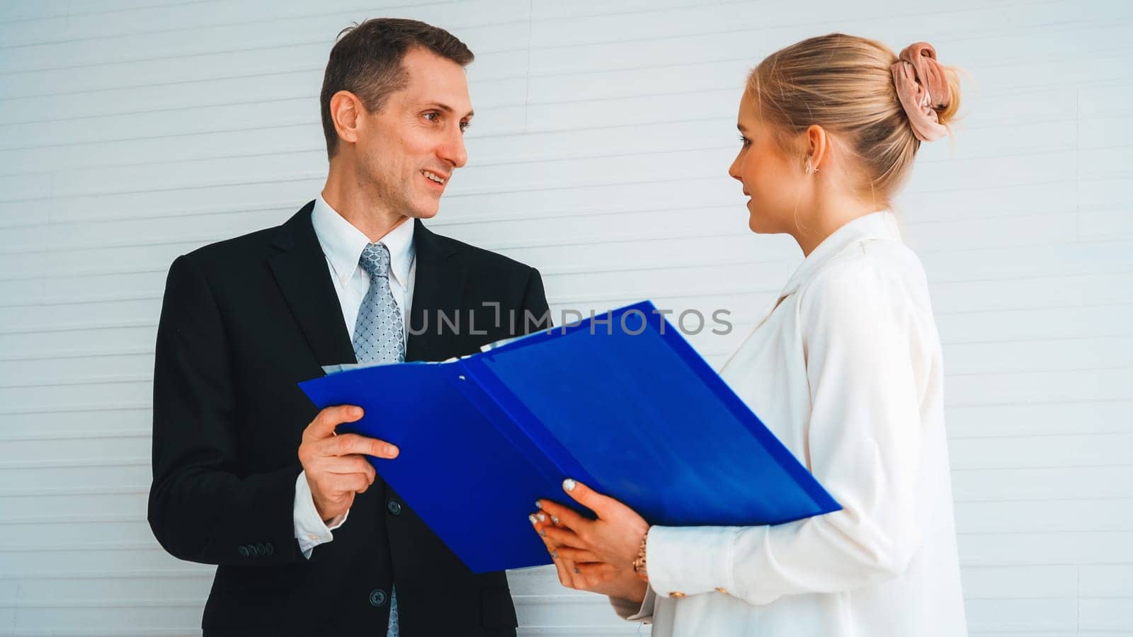 Two business people talk project strategy at office meeting room. Businessman discuss project planning with colleague at modern workplace while having conversation and advice on financial report. Jivy