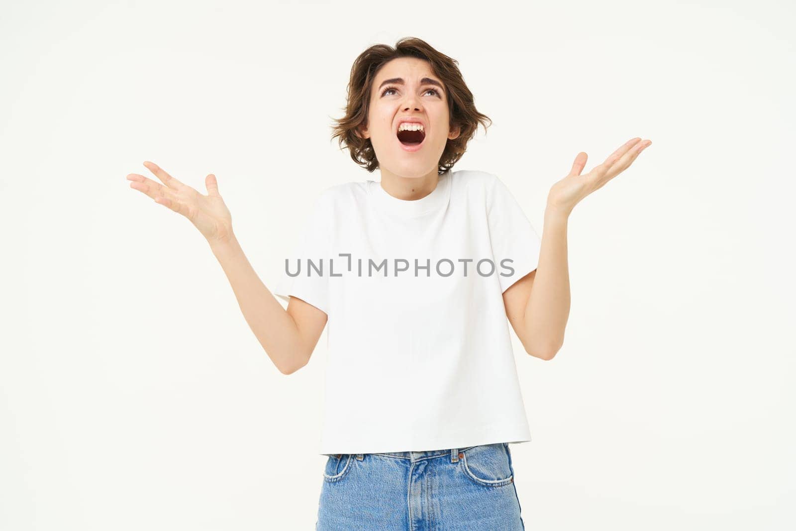 Frustrated young woman, looking upset and disappointed, complaining, screaming from distress and anger, standing over white studio background.