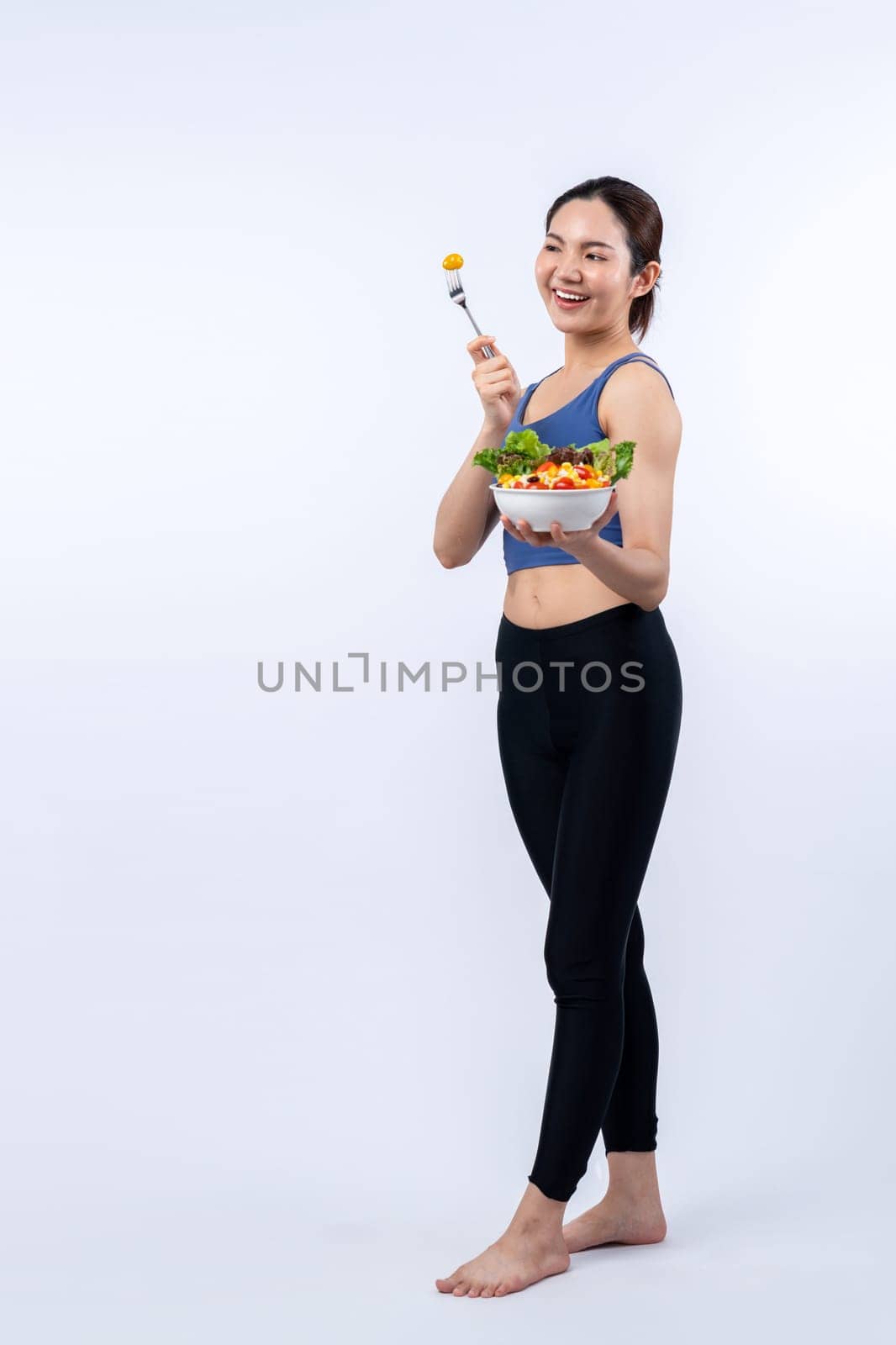 Asian woman in sportswear holding salad bowl on isolated background. Vigorous by biancoblue