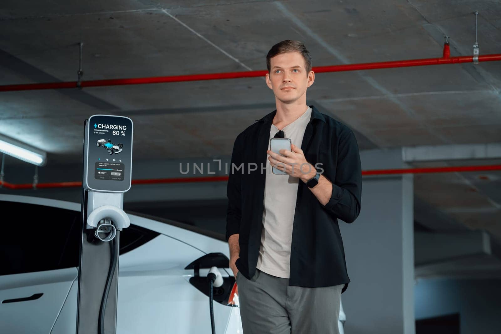 Young man travel with EV electric car to shopping center parking lot charging in downtown city showing urban sustainability lifestyle by green clean rechargeable energy of electric vehicle innards