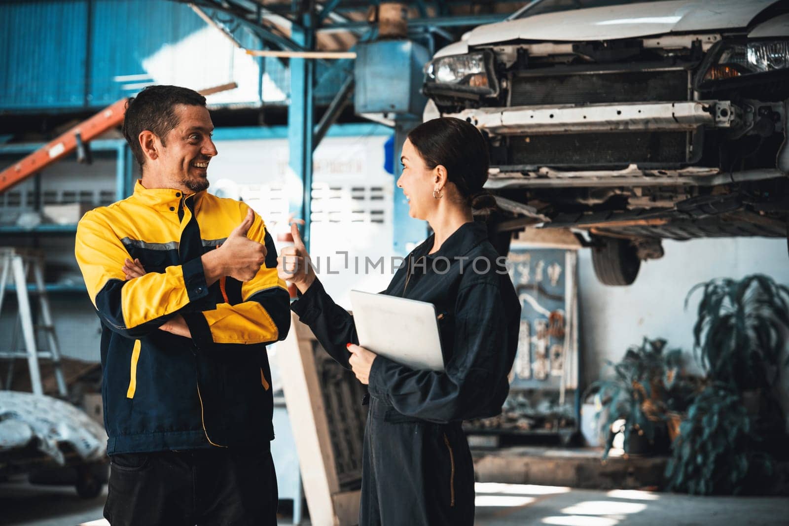Technician team enjoy accomplishment together in garage. Oxus by biancoblue