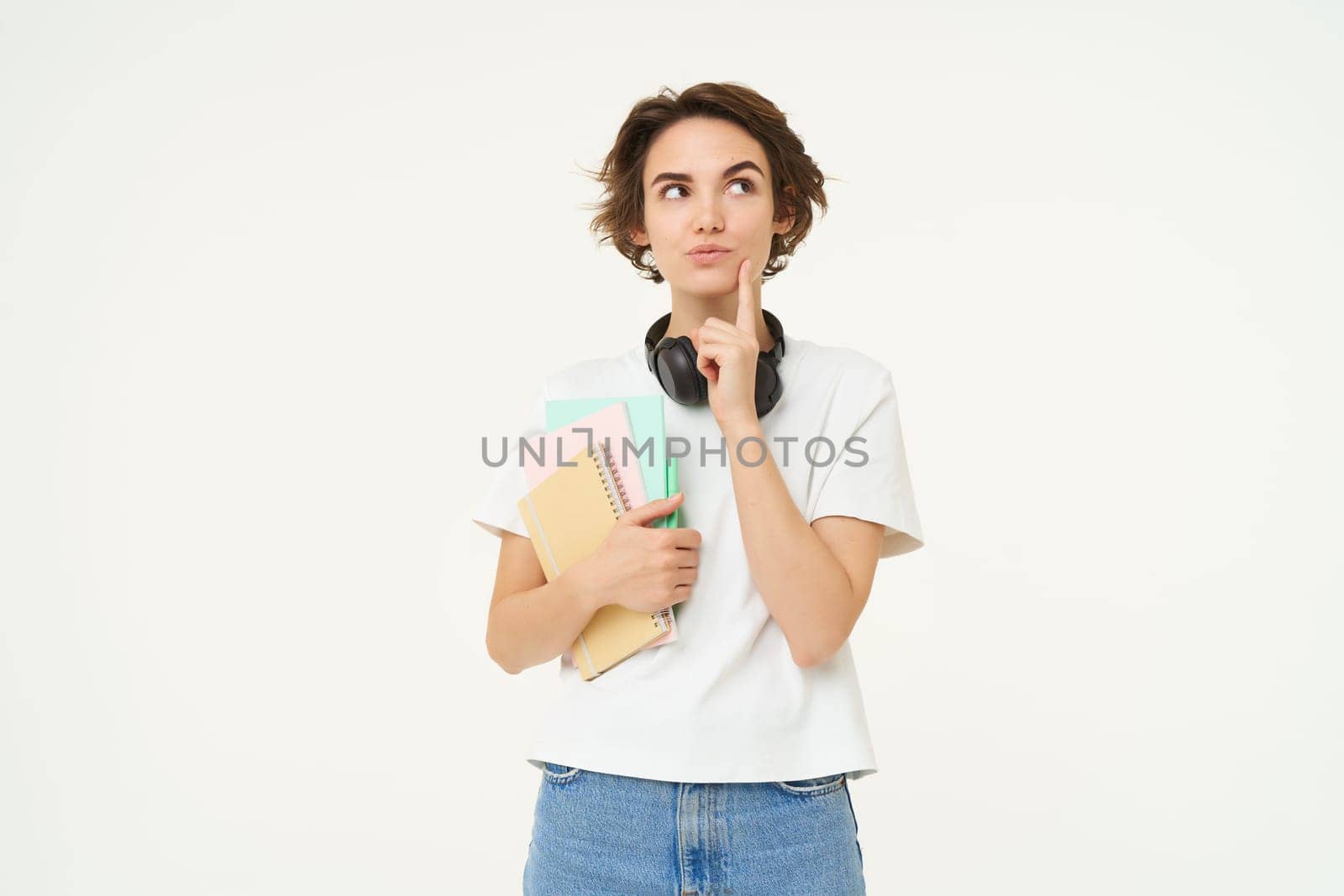 Portrait of brunette woman thinking, student with notebooks, looking thoughtful, making decision, standing over white studio background by Benzoix