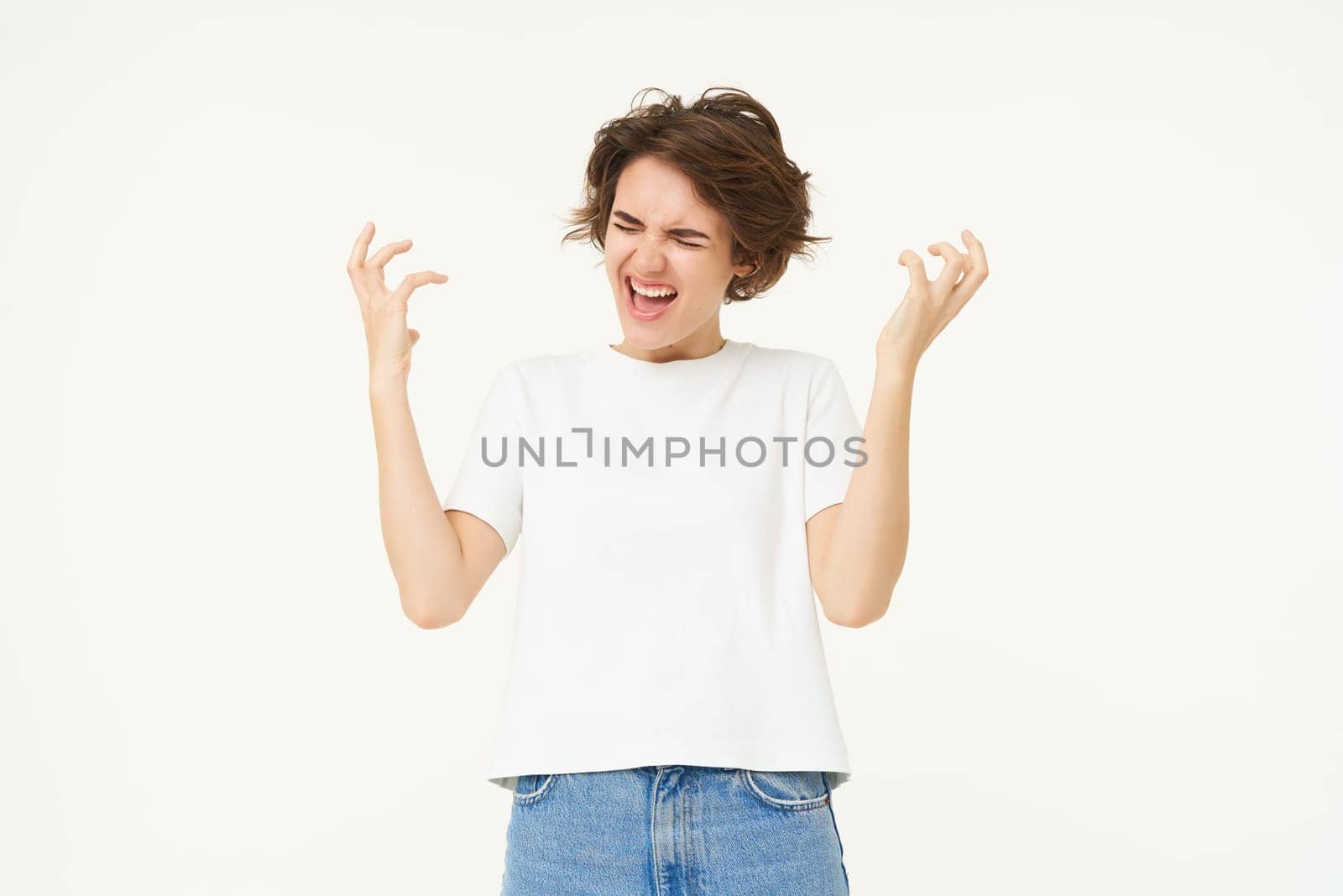 Portrait of woman celebrating, winning prize, triumphing, standing over white studio background.