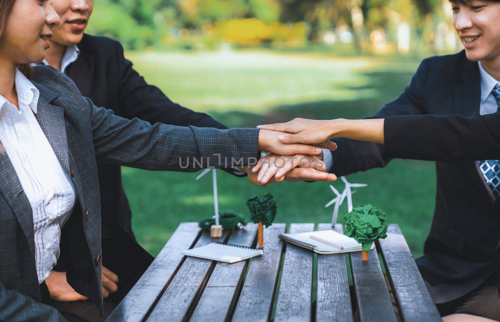 Business people join hand together as teamwork and unity, outdoor business meeting table. Eco-friendly practices and collaboration in corporate social responsibility for greener environment. Gyre