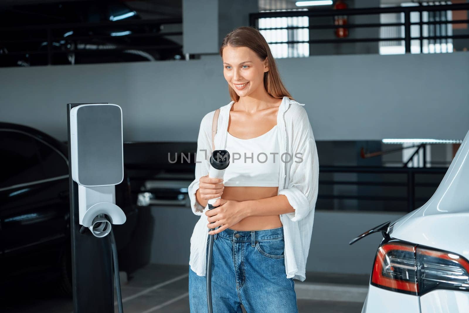 Young woman travel with EV electric car to shopping center parking lot innards by biancoblue