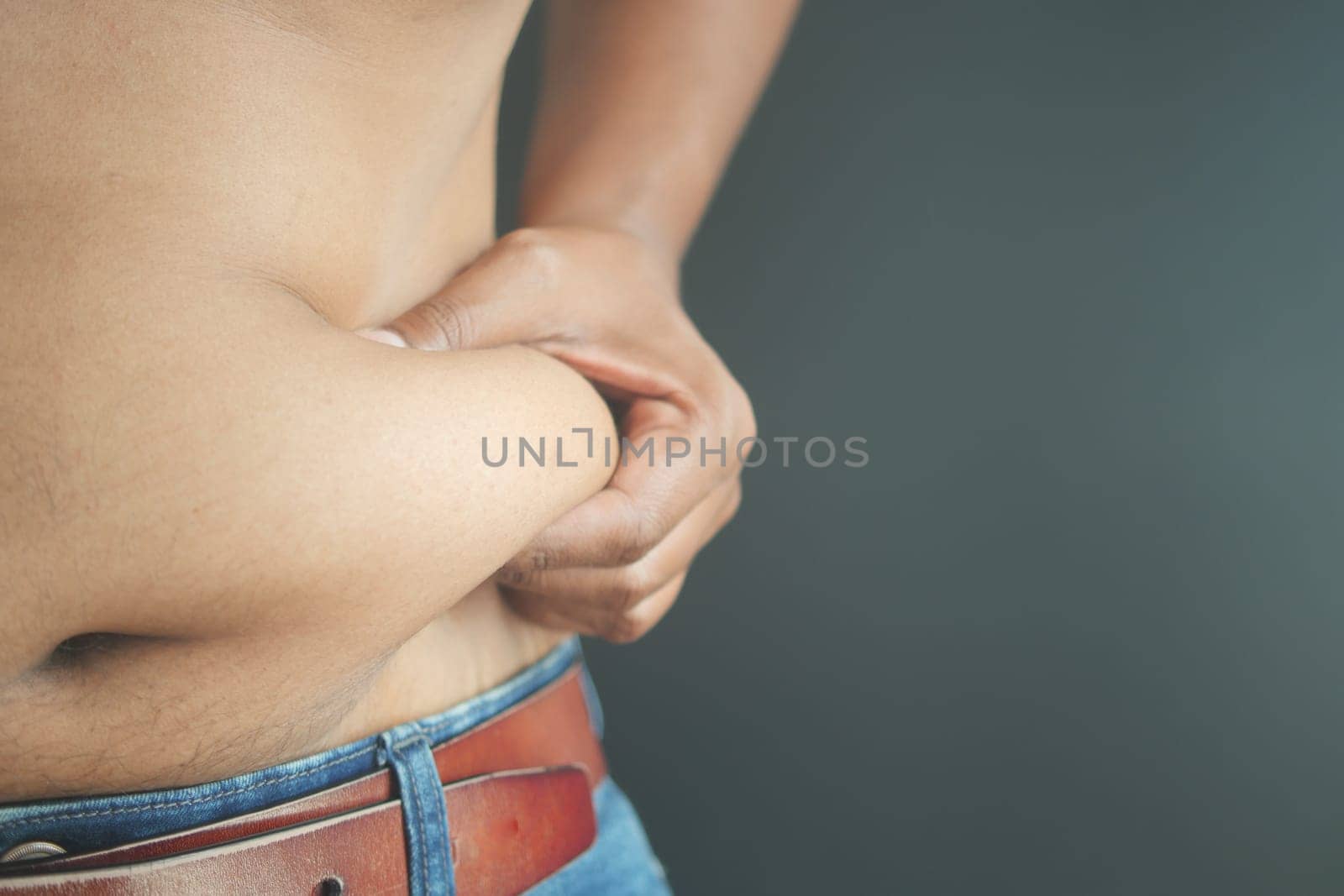 man's hand holding excessive belly fat, overweight concept by towfiq007