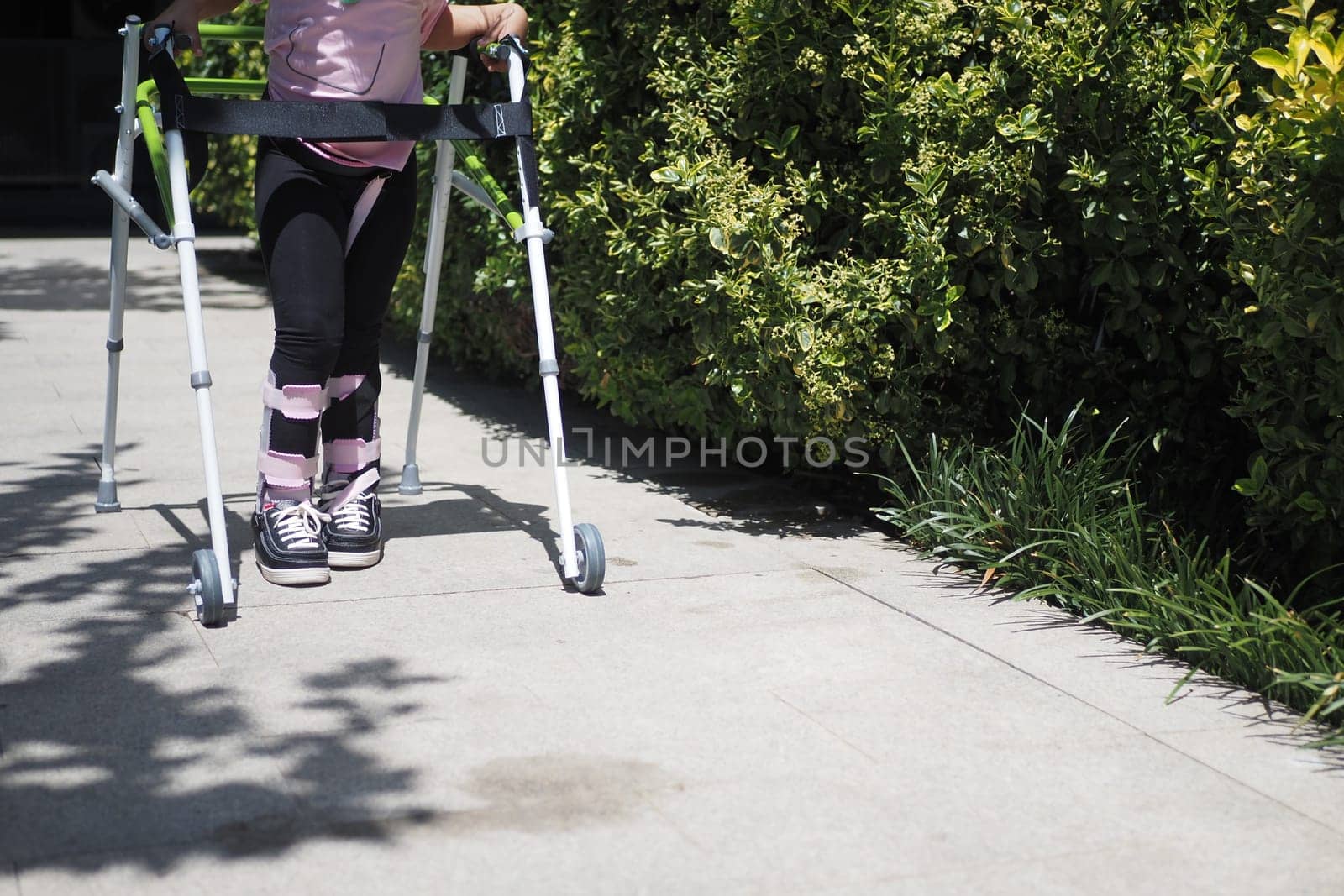 child with walking frame and knee orthosis outdoor by towfiq007