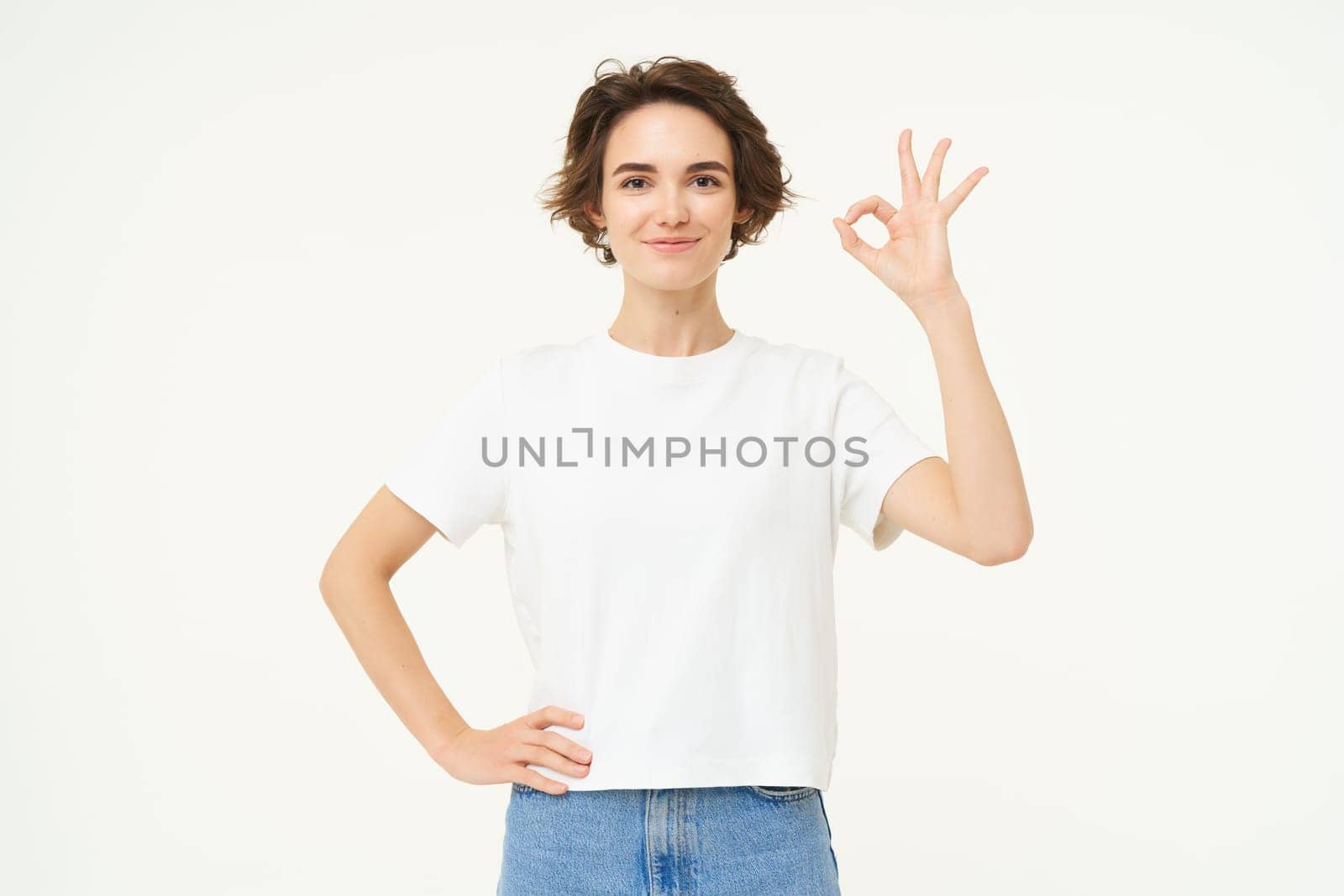 No problem. Portrait of young woman standing in confident pose, shows okay, ok, zero gesture, stands over white studio background by Benzoix