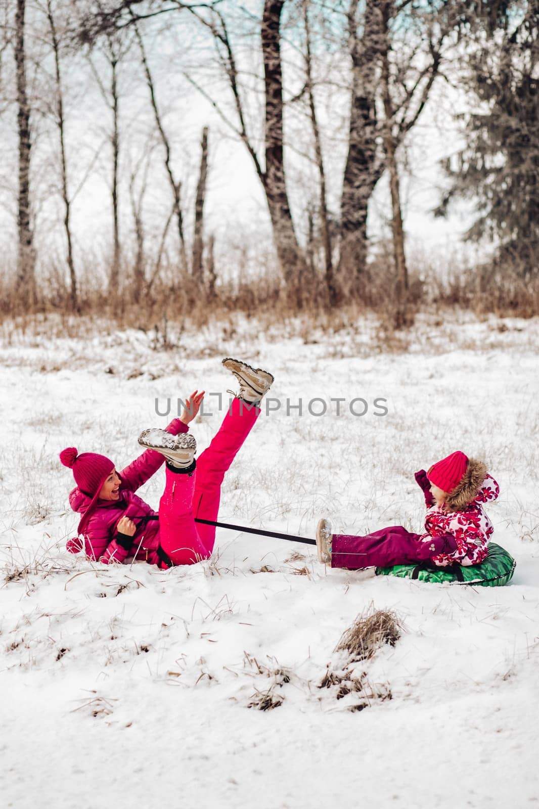 Cute family have fun in a winter park.Mom and daughter play in winter in warm clothes, have fun, hug, rejoice. Family Day
