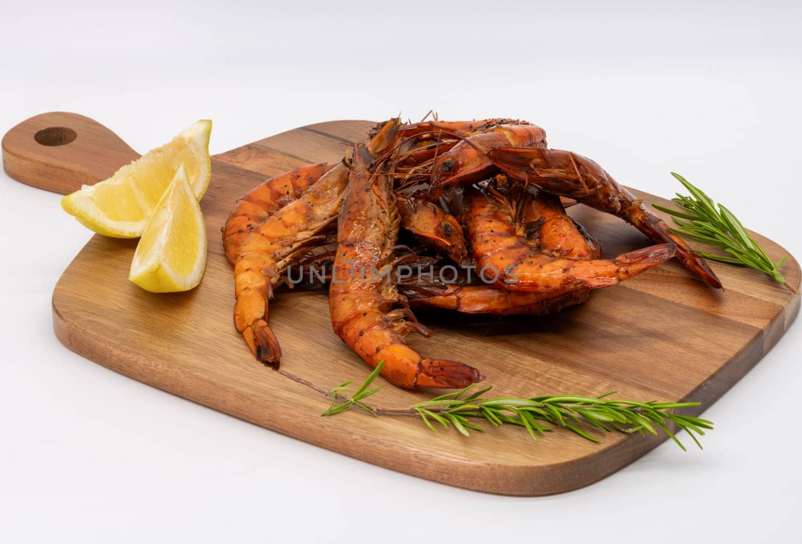 Grilled shrimp garnished with vibrant lemon slices and fresh herbs on a rustic wooden cutting board
