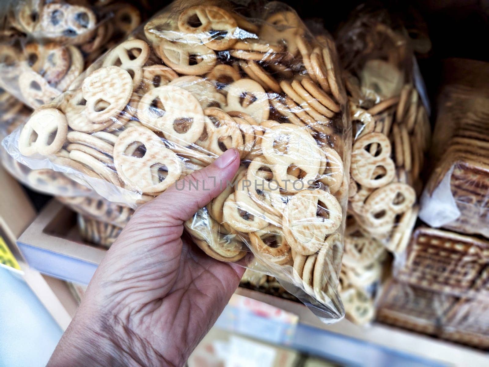 A person selects a bag of delicious cookies while shopping at a local store. Difficult balancing treats with a healthy lifestyle choice