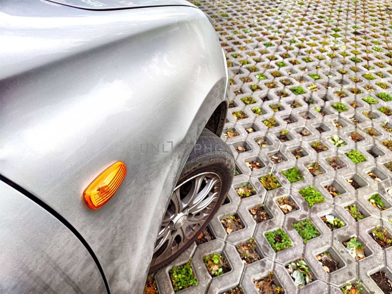 A car parks on an innovative eco-friendly surface designed to promote water absorption and support plant life in an urban setting.