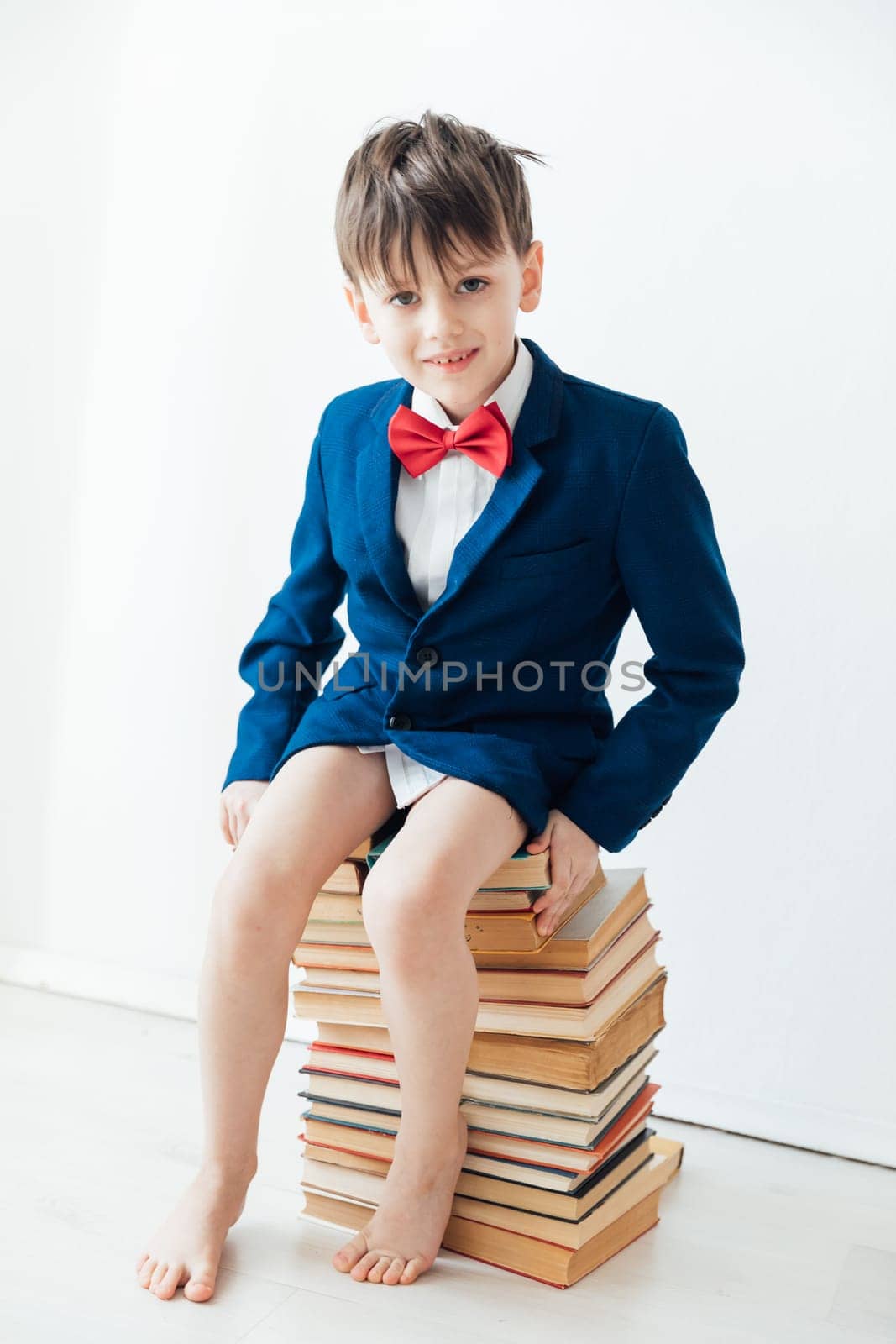 Boy in business suit without pants sitting on books