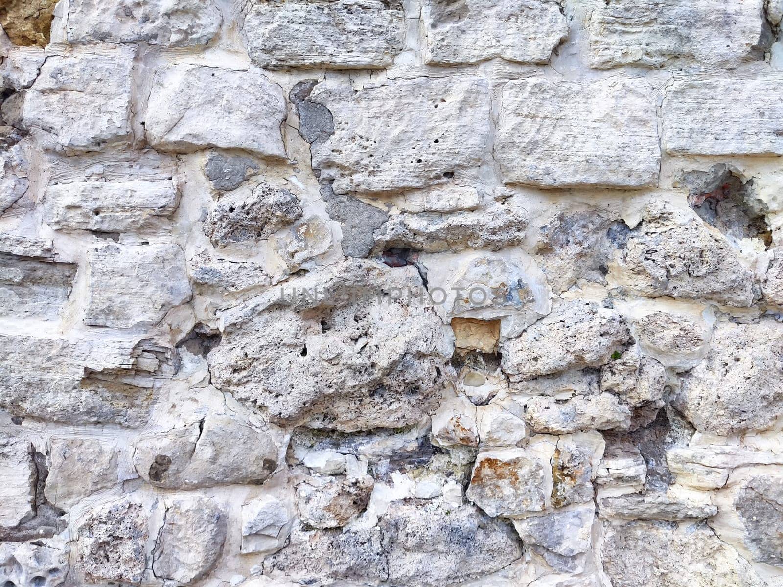Close-up of a rough stone wall exhibiting unique textures and colors, showcasing the beauty of natural aging and erosion.