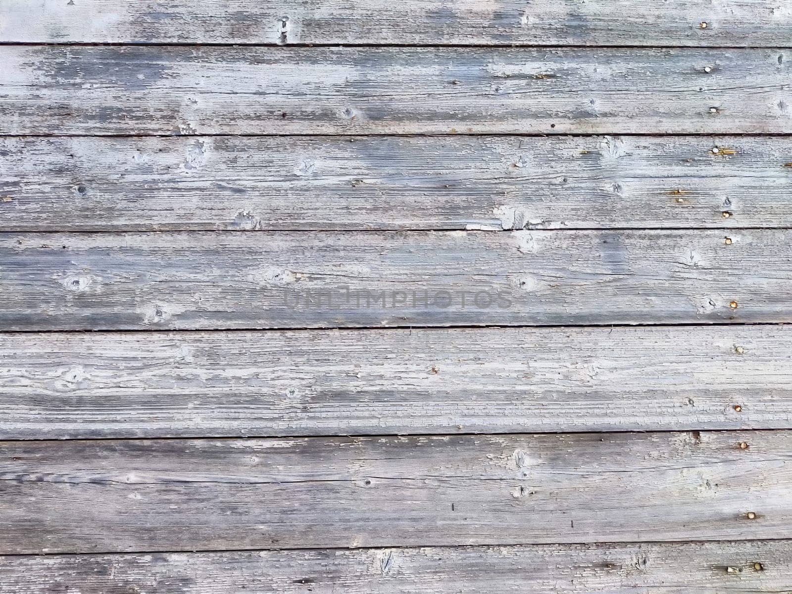 Horizontal wooden planks display a weathered gray finish, showcasing their rustic texture and character.