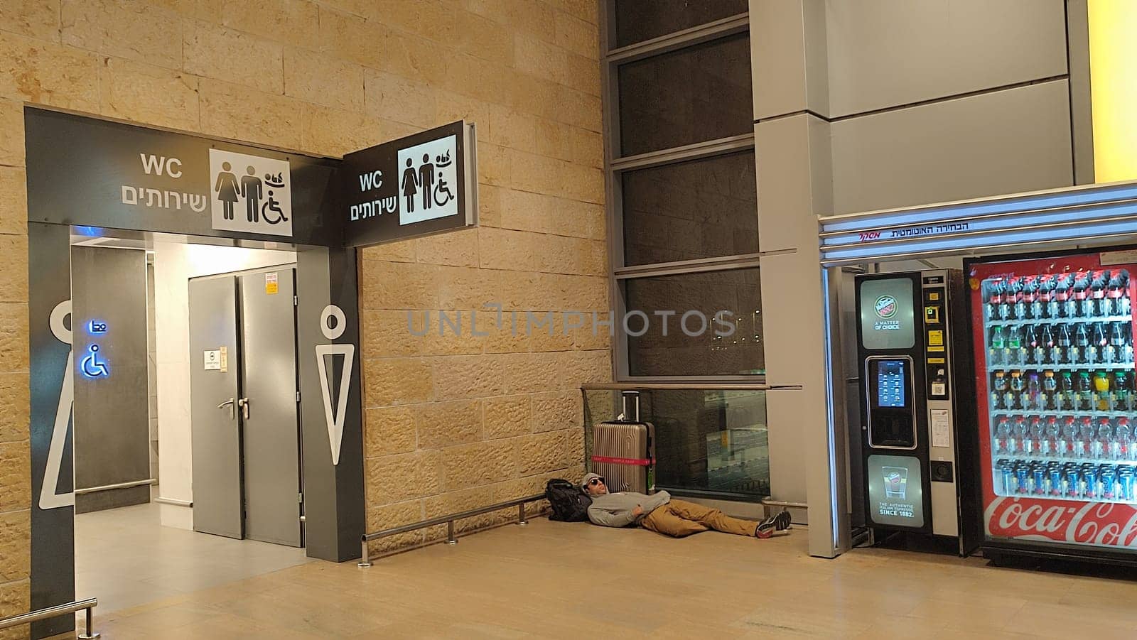 15 October 2024 Tel-Aviv Israel Ben Gurion airport Terminal 3, travel lounge, Male tourist sleeping on the floor near a suitcase, quality photo