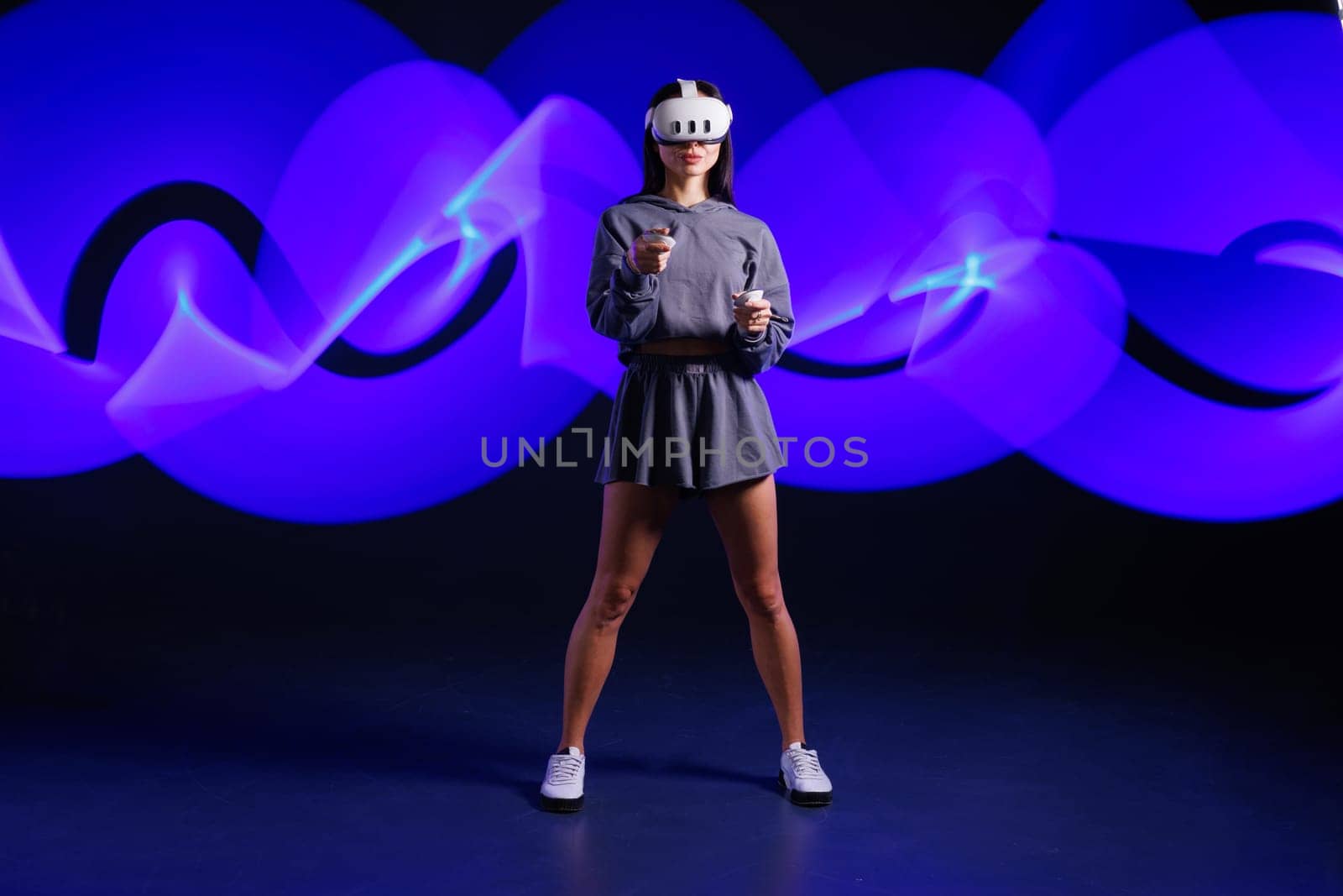 VR, AR, MR, XR Future technologies. Neon. Young girl in VR glasses in neon doing sports and playing a game. Concept of modern gadgets and technologies