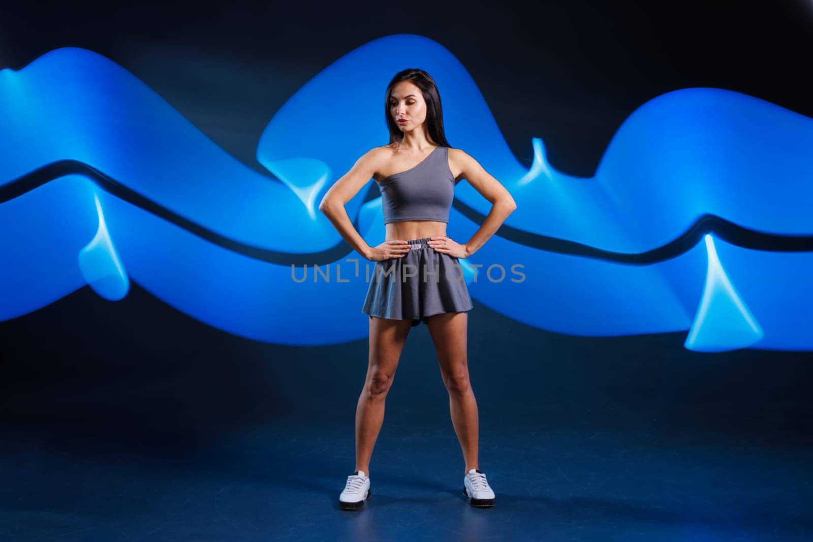 young girl athlete doing sports in neon light on dark background, concept modern sports training