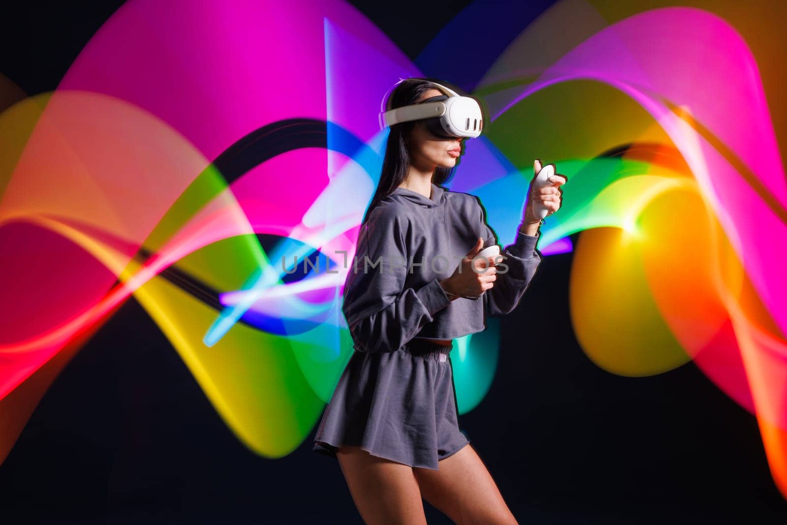 VR, AR, MR, XR Future technologies. Neon. Young girl in VR glasses in neon doing sports and playing a game. Concept of modern gadgets and technologies