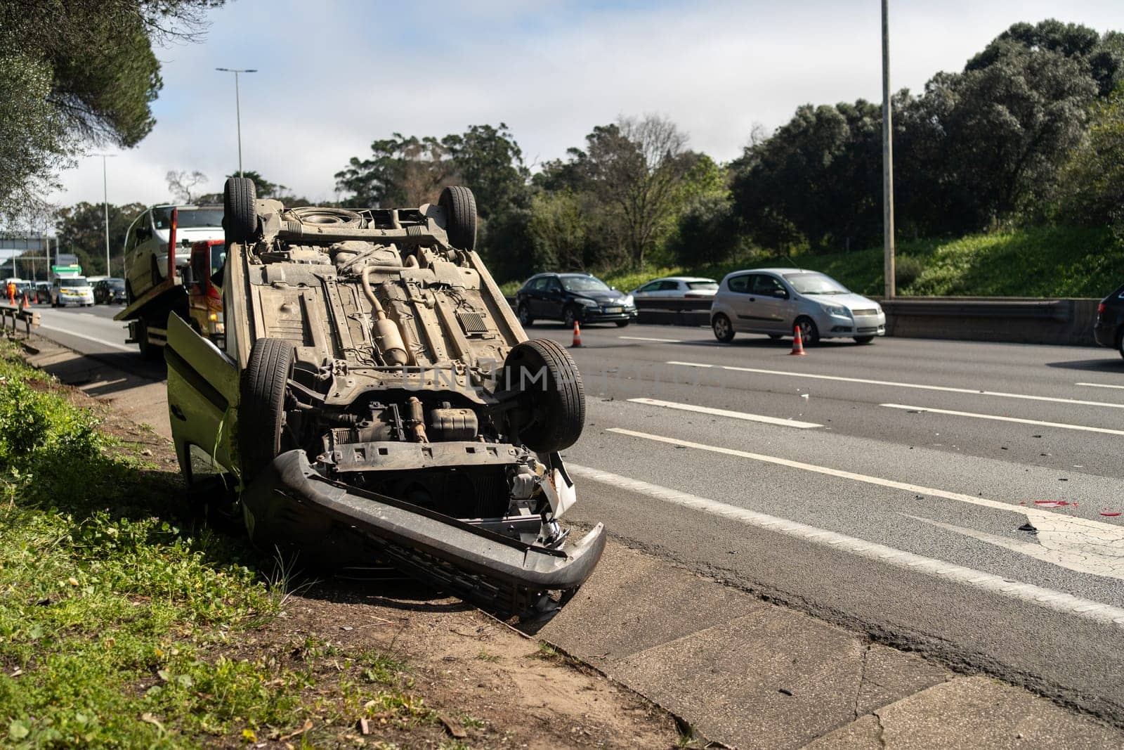 Damaged wrecked car after collision lying upside down on roadside. Busy city street with car rolled over during daytime. Car accident